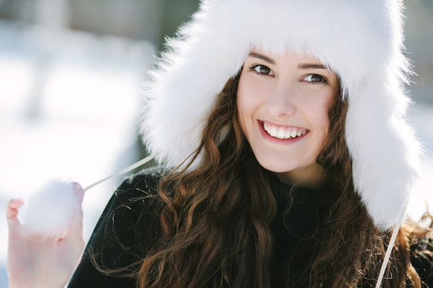 Hermosa joven sonriente con sombrero de piel blanca