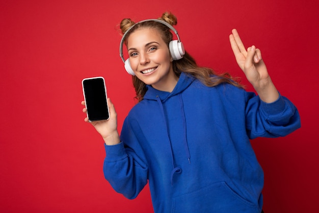 Hermosa joven sonriente vistiendo elegante sudadera con capucha azul aislado