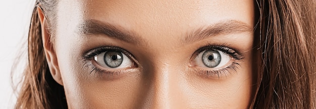 Hermosa joven se sorprende y mira a la cámara sobre un fondo blanco aislado. Mujer morena positiva. Mirada amable. Belleza cara y ojos