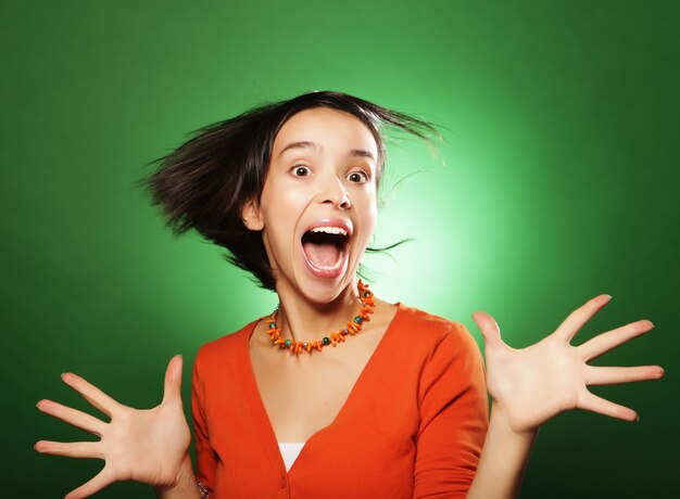 Hermosa joven sorprendida sobre fondo verde