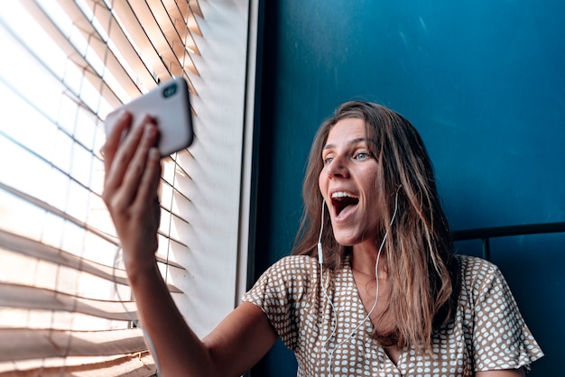 Una hermosa joven sorprendida durante una videollamada en el momento.