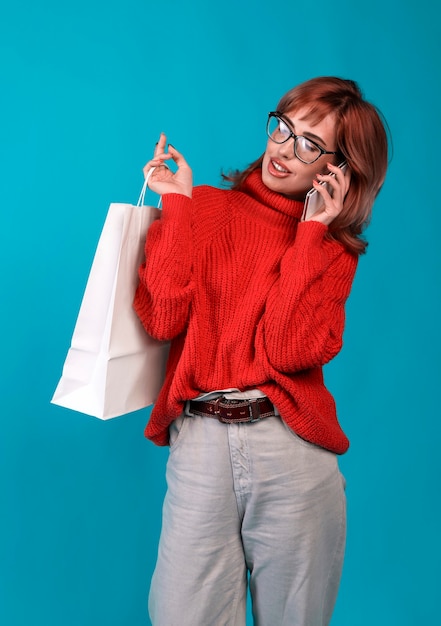 Hermosa joven sosteniendo una bolsa de papel en blanco blanco y realiza compras en una tienda online contra