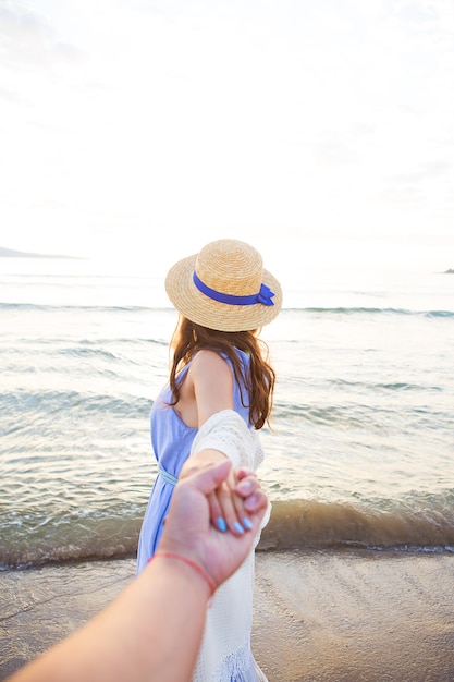 Hermosa joven sosteniendo a un chico de la mano y mirando el mar