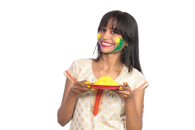 Hermosa joven sosteniendo color en polvo en placa con motivo del festival de Holi