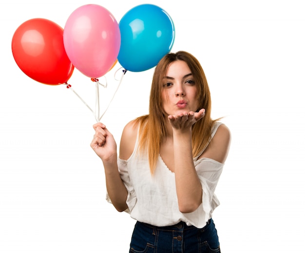 Hermosa joven sosteniendo un globo y enviando un beso