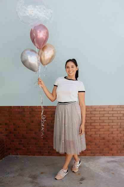 Hermosa joven sosteniendo globos de gas