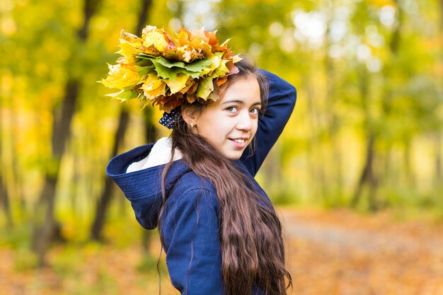 Hermosa joven sosteniendo hojas amarillas en el parque otoño