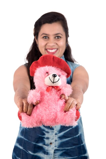 Foto hermosa joven sosteniendo y jugando con un osito de peluche en un blanco.