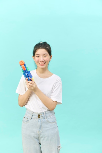 Hermosa joven sosteniendo una pistola de agua en el festival Songkran de Tailandia aislada de fondo azul.