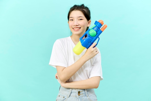 Hermosa joven sosteniendo una pistola de agua en el festival Songkran de Tailandia aislada de fondo azul.