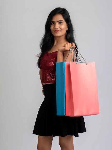 Hermosa joven sosteniendo y posando con bolsas de la compra.