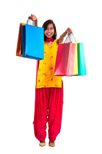 Hermosa joven sosteniendo y posando con bolsas de compras en un fondo blanco