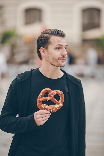 Hermosa joven sosteniendo pretzel y relajarse en el parque