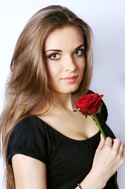 Hermosa joven sostiene una rosa roja