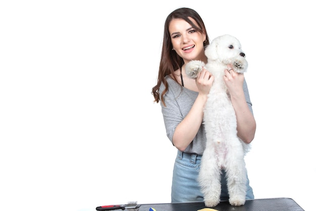 Una hermosa joven sostiene a su cachorro bichón