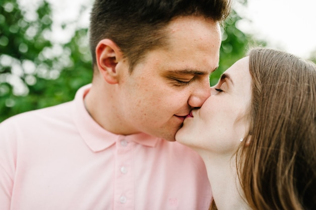 Foto hermosa joven y su esposo se besan con los ojos cerrados en el contexto de la naturaleza