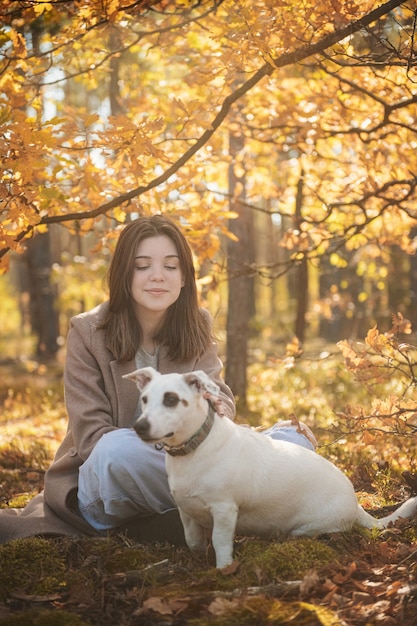 Hermosa Joven Con Su Perro En El Bosque. Bosque de otoño.