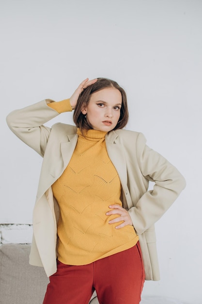 Una hermosa joven con un suéter mostaza y una chaqueta beige