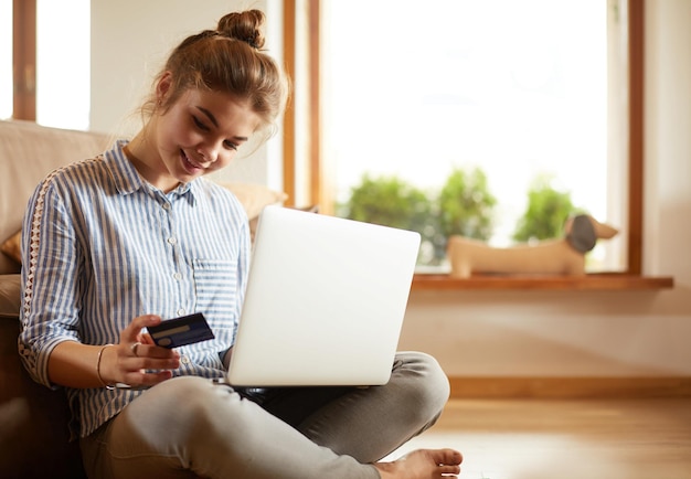 Foto hermosa joven con tarjeta de crédito y computadora portátil para compras en línea