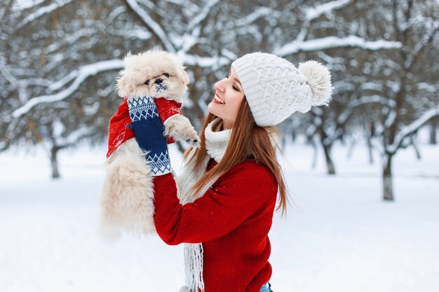 Hermosa joven tiene perrito en sus manos y jugando con él