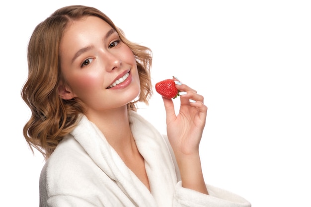 Hermosa joven tierna con una bata blanca con piel limpia y fresca posando delante de la cámara. Rostro de belleza. Protección de la piel. Foto tomada en estudio sobre un fondo blanco aislado.