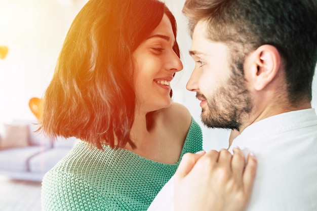 Hermosa joven tierna pareja encantadora se besan y se abrazan mientras se sientan en el suelo del dormitorio con un fondo romántico. Día de San Valentín. Aniversario. Fecha. concepto de amor