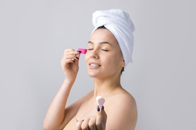 Hermosa joven con una toalla blanca en la cabeza usa parches de gel de colágeno debajo de los ojos