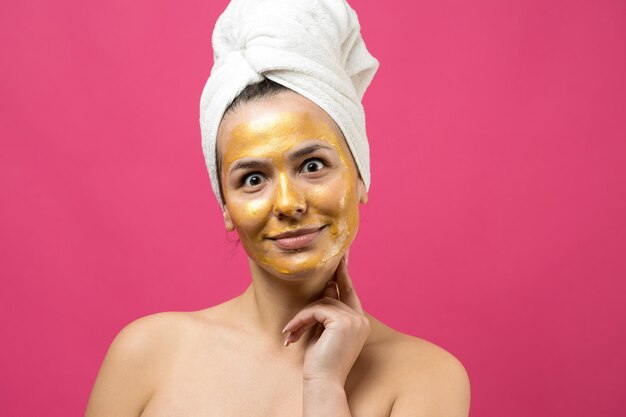 Hermosa joven con una toalla blanca en la cabeza usa parches de gel de colágeno debajo de los ojos