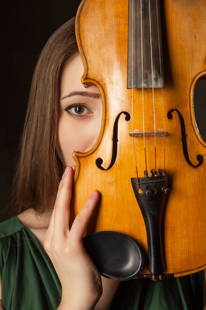 Hermosa joven tocando el violín sobre fondo negro