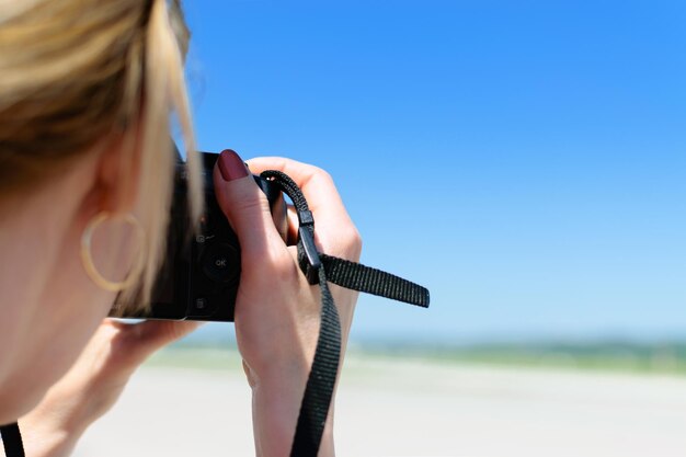 Hermosa joven toma una foto en la playa con una cámara DSLR profesional