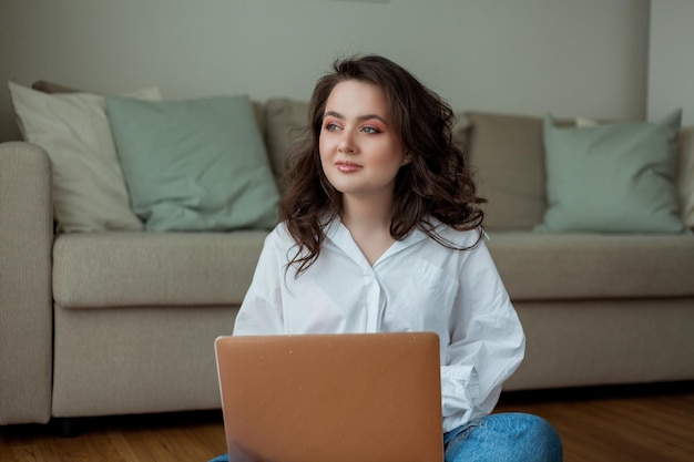 Hermosa joven trabaja en línea en casa con una computadora portátil Oficina en el hogar Estudiar en línea Redes sociales Conversación en video Casa acogedora