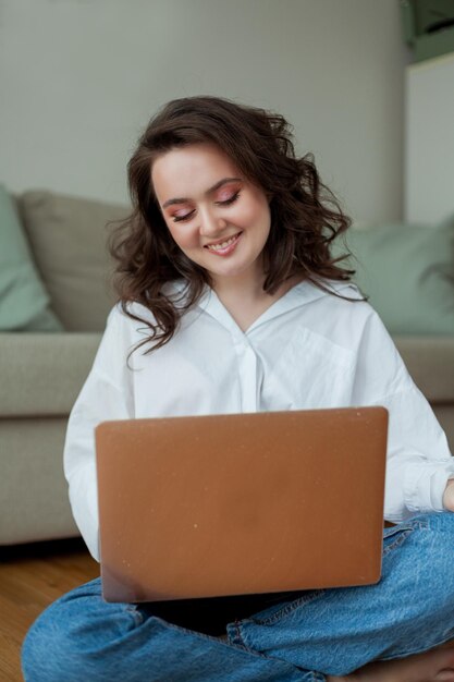 Hermosa joven trabaja en línea en casa con una computadora portátil Oficina en el hogar Estudiar en línea Redes sociales Conversación en video Casa acogedora