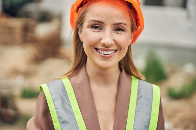 Hermosa joven trabajadora rubia con una sonrisa feliz mirando hacia adelante