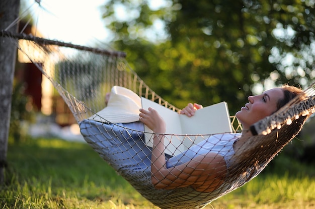 Hermosa joven tumbada y leyendo un libro en el verano al aire libre