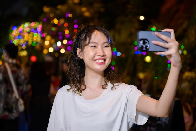 Hermosa joven turista asiática de vacaciones haciendo turismo y explorando en la calle Khao San por la noche