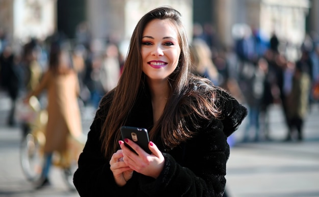 Hermosa joven turista en Milán con un teléfono inteligente