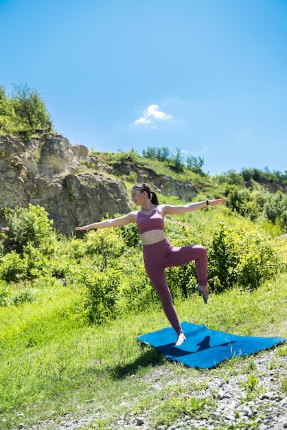 Hermosa joven con uniforme deportivo cerca de las rocas se dedica a estirarse al aire libre