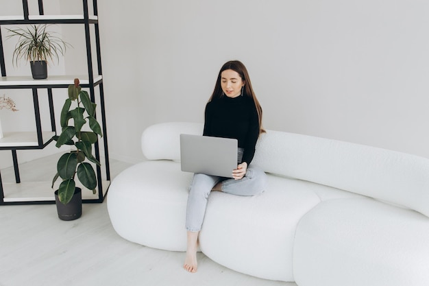 Hermosa joven usando la computadora portátil en casa