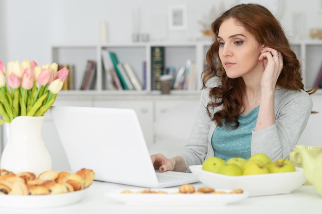 Hermosa joven usando laptop en la mesa