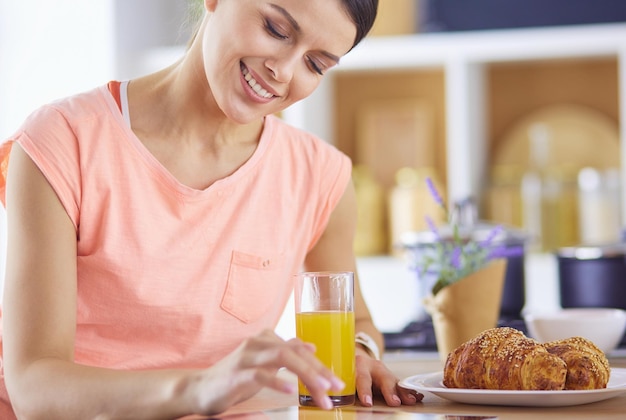 Hermosa joven usando una tableta digital en la cocina