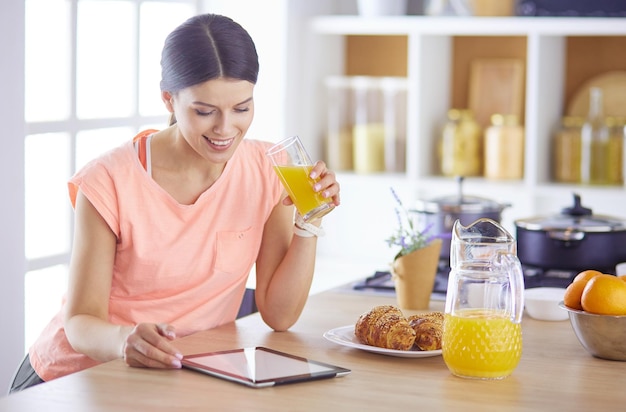 Hermosa joven usando una tableta digital en la cocina