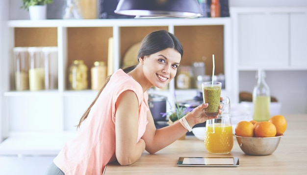 Hermosa joven usando una tableta digital en la cocina