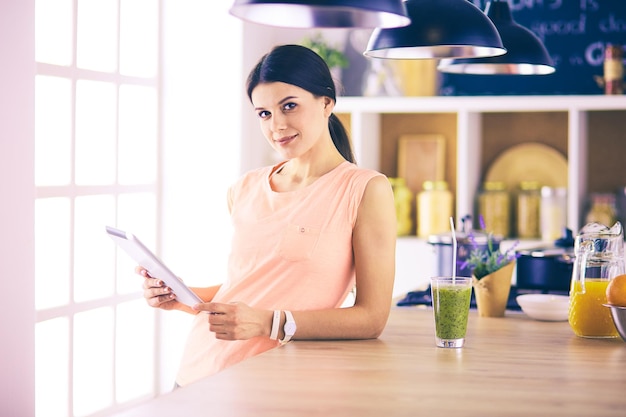 Hermosa joven usando una tableta digital en la cocina