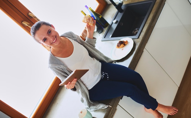 Hermosa joven usando una tableta digital en la cocina