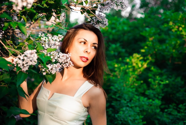 Foto hermosa joven en el verano en el parque al atardecer en un vestido sonriendo