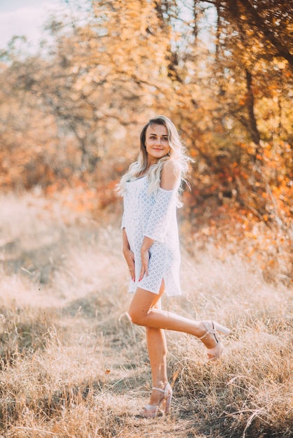 Hermosa joven vestida de blanco, en el bosque de otoño es muy hermosa y fácil