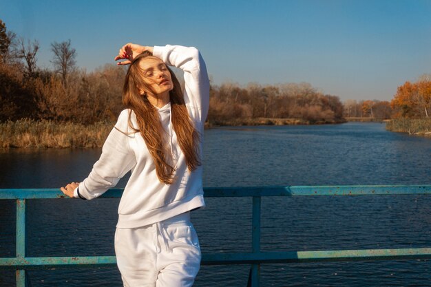 Hermosa joven vestida de blanco se encuentra en el puente