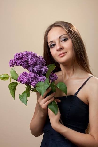 Hermosa joven vestida de negro con un ramo de lilas