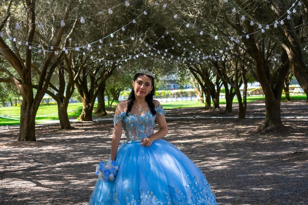 Hermosa joven vestida con un traje de princesa azul claro, en un paisaje de árboles