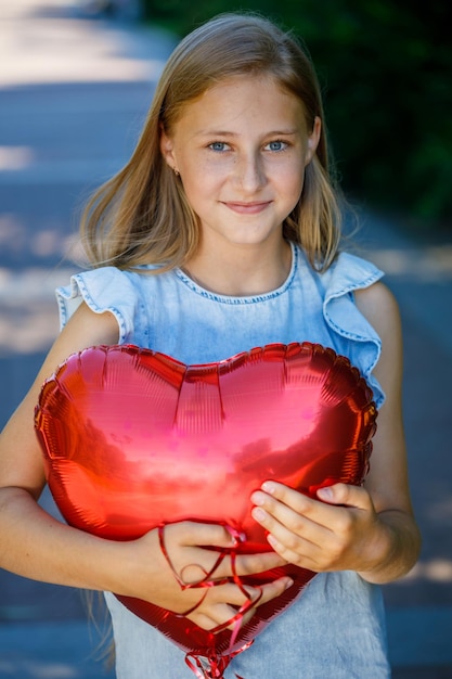 Hermosa joven con un vestido azul con un globo en forma de corazón